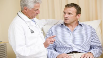 Doctor giving man checkup in exam room